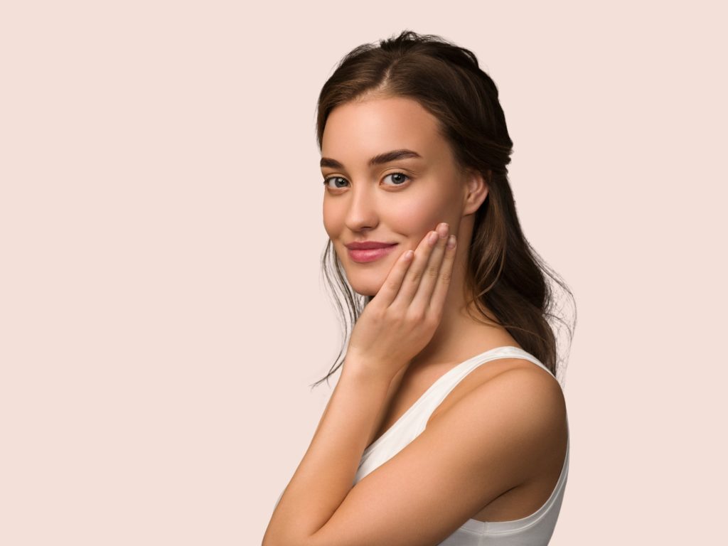 Beauty woman face healthy skin care female beautiful woman Touching her face. Color pink background